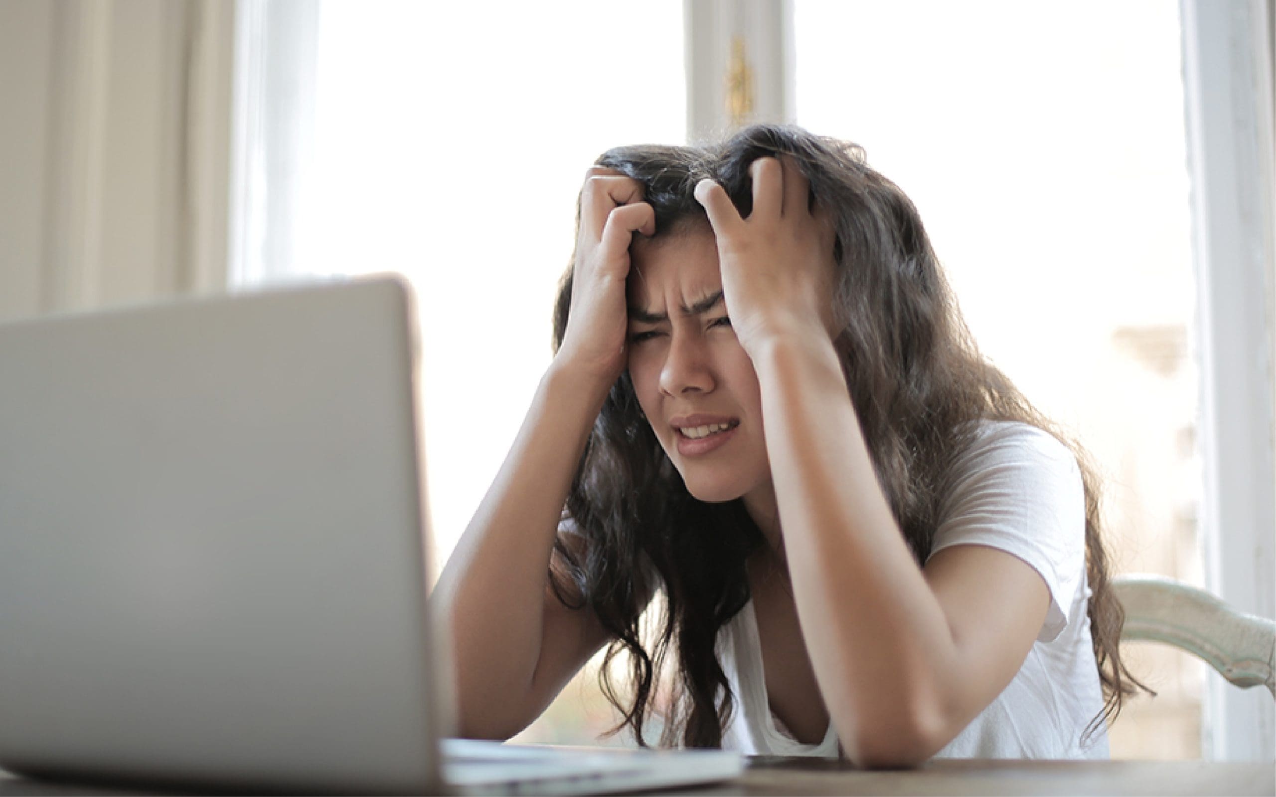 woman looking anxious in-front of a laptop