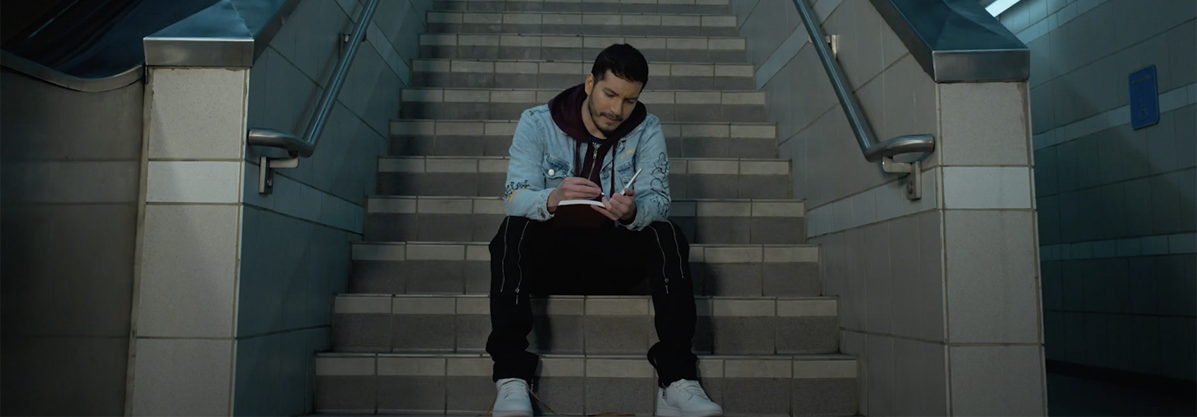 man sitting on stairs writing diary